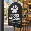Black 3D printed Dogs Welcome sign with paw print, displayed in a café window