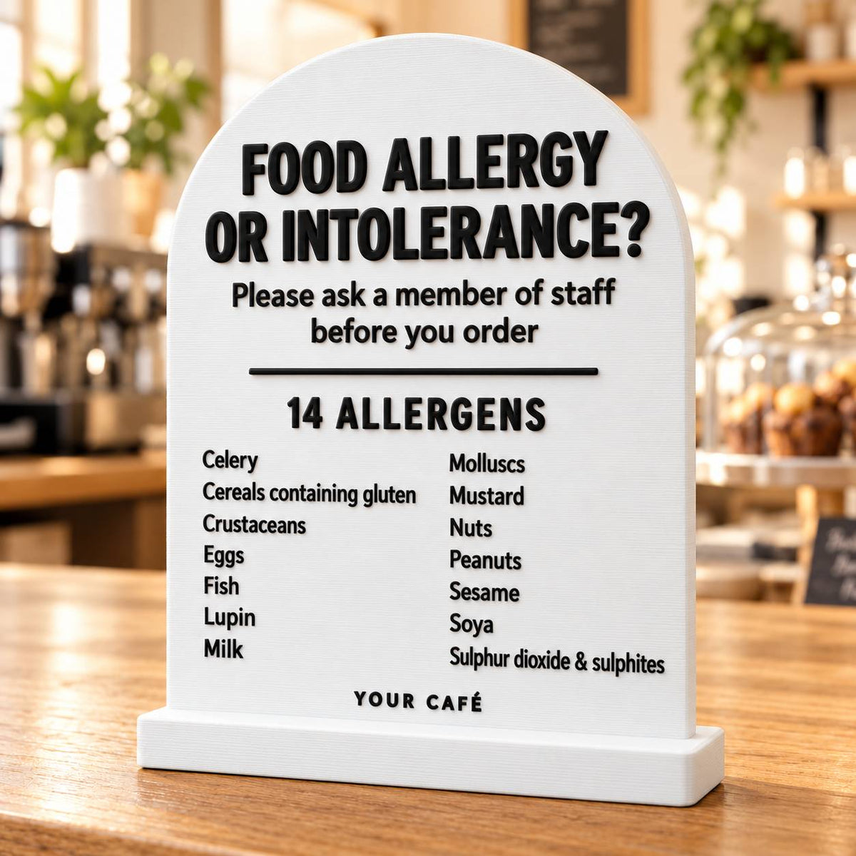 White 3D printed allergen sign listing the 14 allergens, standing on a café counter