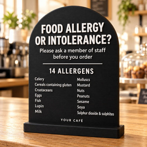 Black 3D printed allergen sign listing the 14 allergens, standing on a café counter